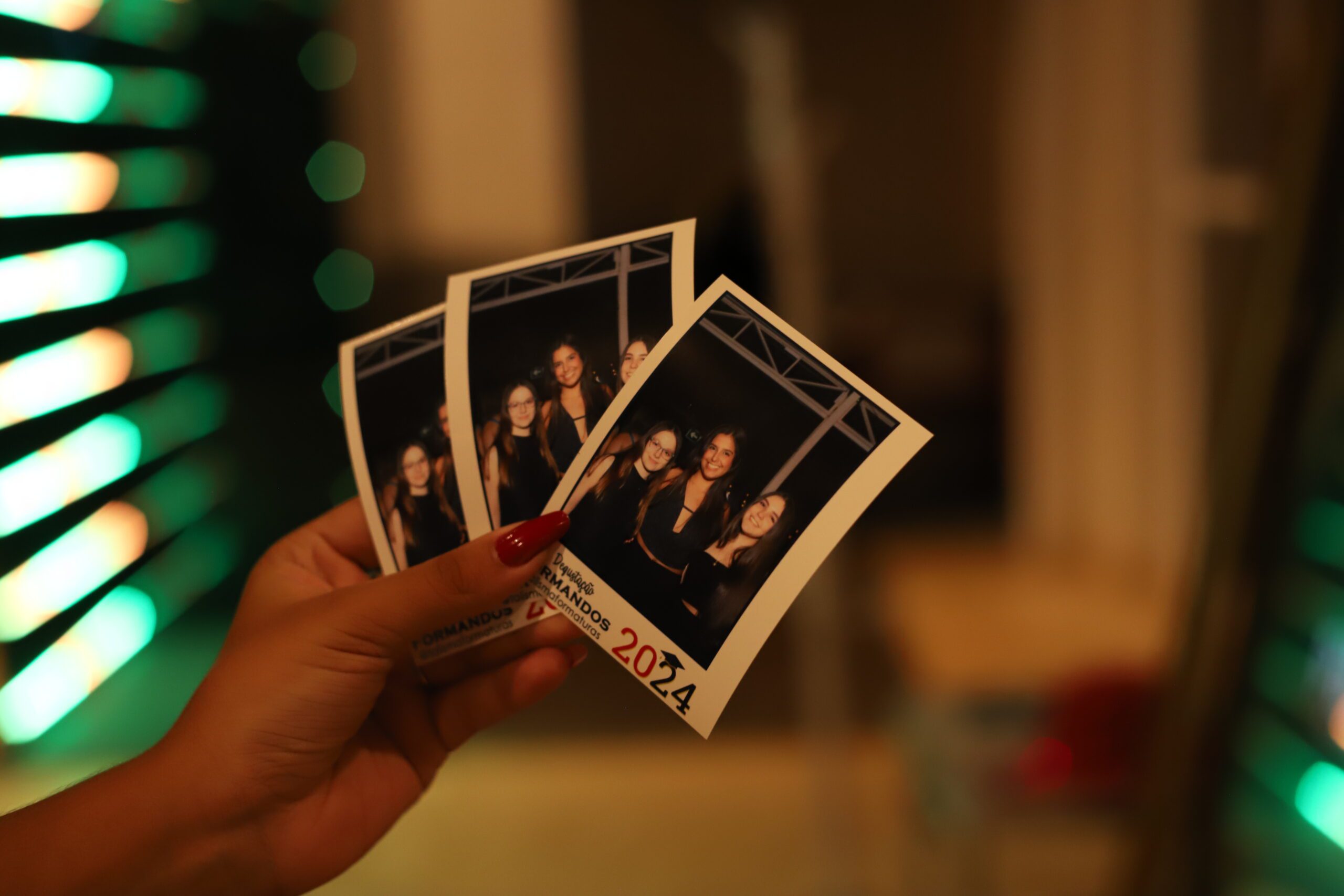 Fotos de formatura impressas nas mãos de uma formanda, lembrança da festa da turma de 2024
