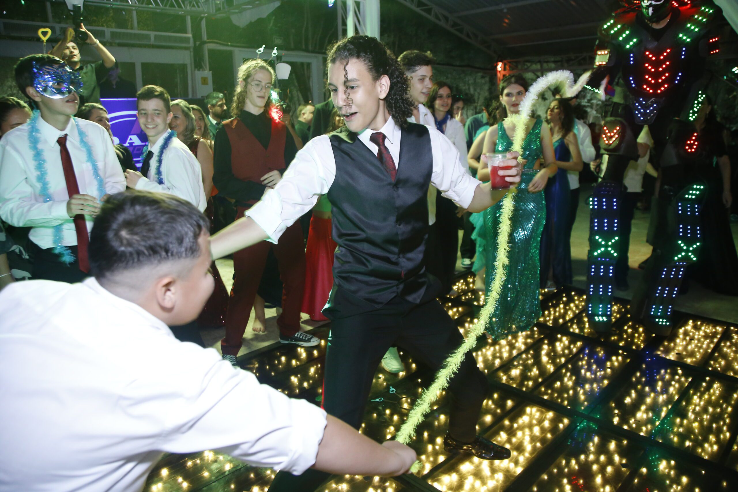 Formando de gravata-borboleta dançando entre os colegas na pista do baile de gala da Talismã Formaturas